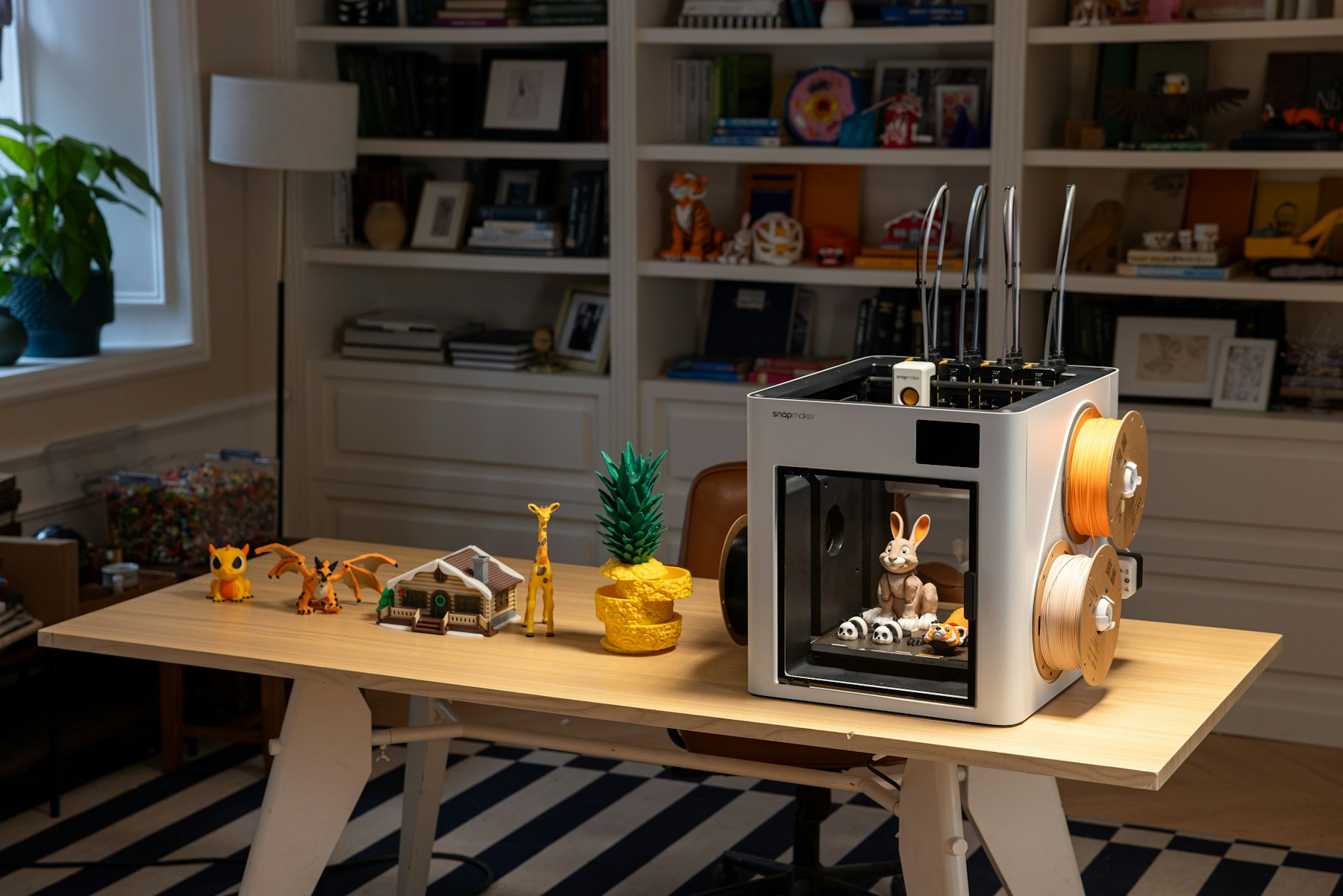 PLA 3D printer with filament and printed objects on a desk
